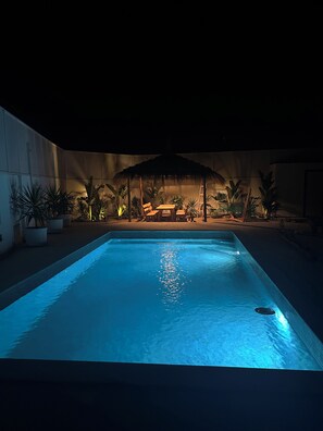 A swimming pool with a lounge area and potted plants around it.