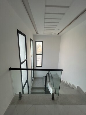A staircase with glass railings and a view of buildings outside.
