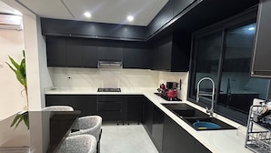 A modern kitchen with a central island, black cabinetry, and a white countertop. - VILLA BLANCA, a vacation villa with a pool and no neighbors in sight. Garage. 4 bedrooms. (Djerba Midun)