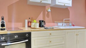 A kitchen with a coffee machine, a kettle, a tea kettle, and a bottle of syrup on the counter. - Le Cocon de Boucan Canot - À 300 m de la plage (La Possession)