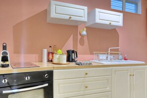 A kitchen with a coffee machine, a kettle, a tea kettle, and a bottle of syrup on the counter. - Le Cocon de Boucan Canot - À 300 m de la plage (La Possession)
