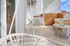 A room with a hammock, a table with a bottle, and a chair. - Le Cocon de Boucan Canot - À 300 m de la plage (La Possession)