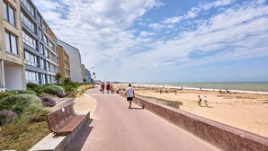 Una passeggiata costiera con edifici su un lato e una spiaggia sull'altro.