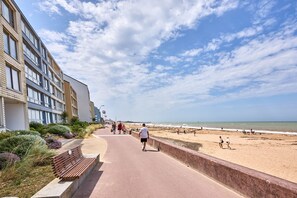 Ein Küstenweg mit Gebäuden an einer Seite und einem Strand an der anderen.