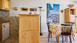 Un'area pranzo con tavolo in legno, sedie e un quadro raffigurante una barca a vela appeso al muro.