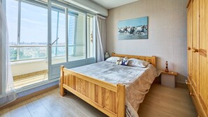 Una camera da letto con un letto di legno, un comodino, un quadro e vista panoramica da ampie finestre.