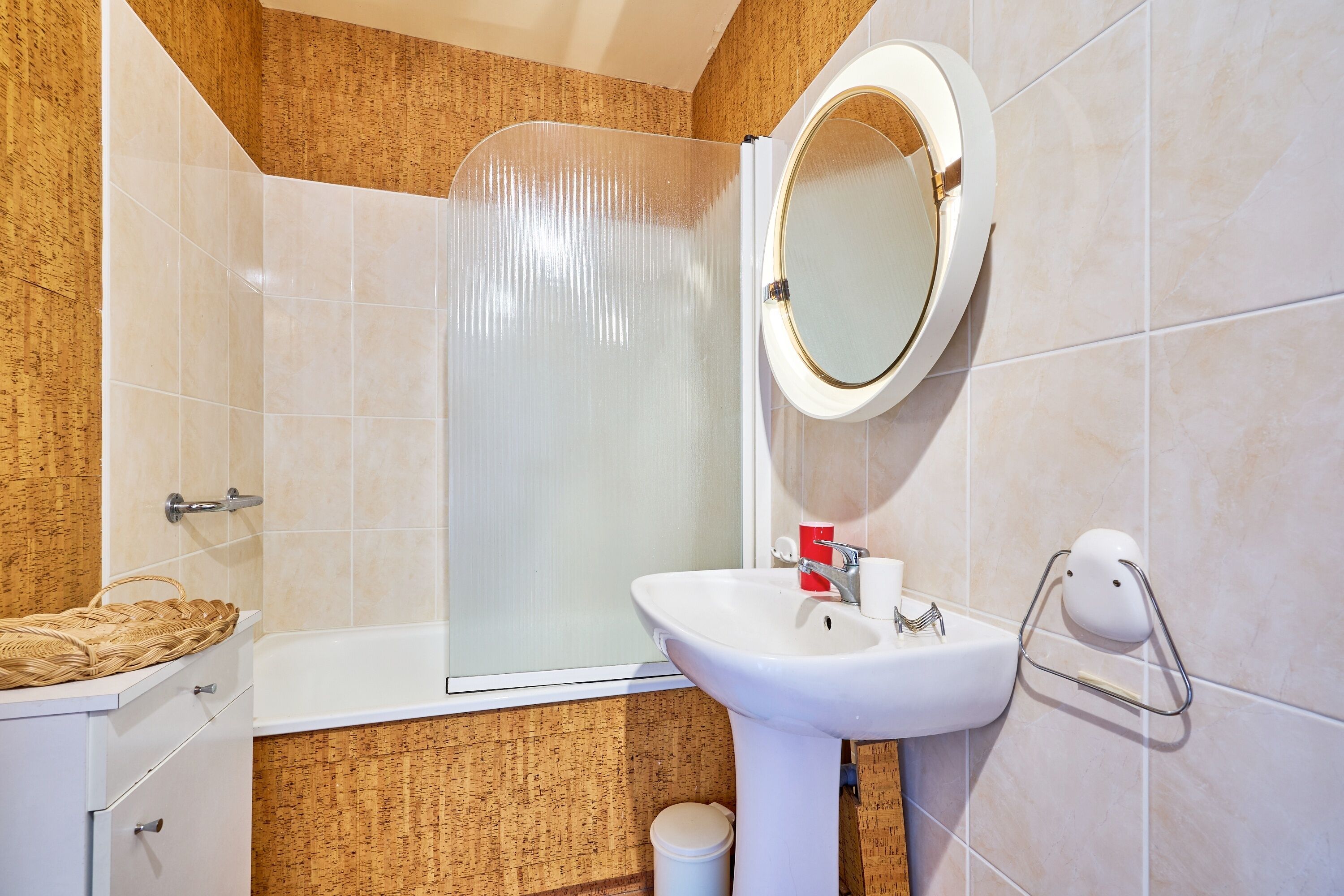 A bathroom with a bathtub, a sink, a mirror, and a toilet.