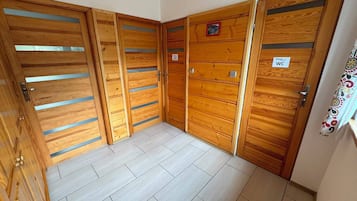 Un conjunto de puertas de madera con un cartel que indica un aseo, un suelo de baldosas y una pequeña foto en la pared.