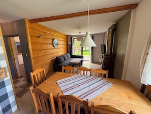 Un comedor con una mesa de madera, sillas, un sofá y una lámpara colgante.
