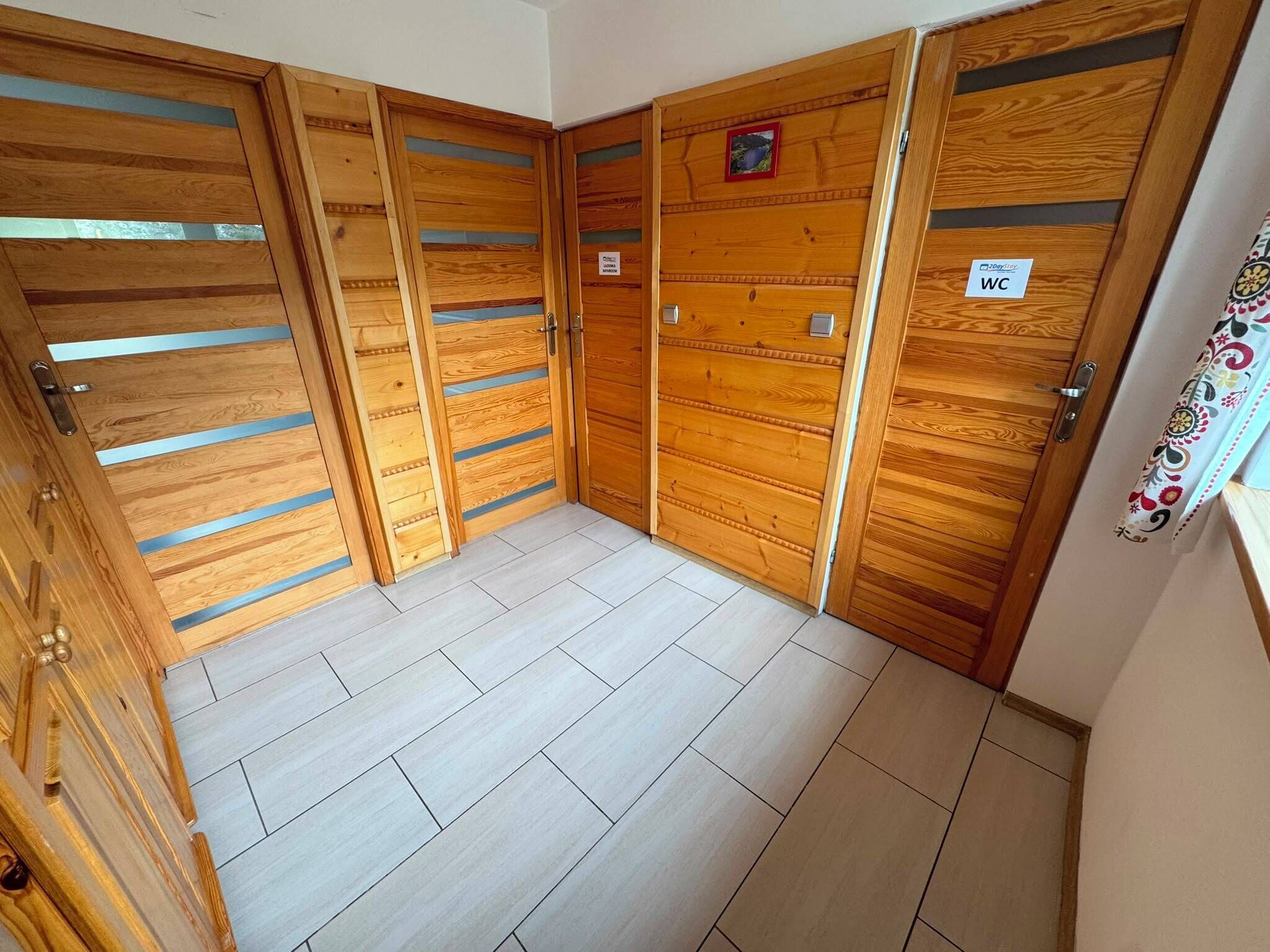 Una habitación con puertas correderas de madera, suelo de baldosas y un cartel que indica un baño.