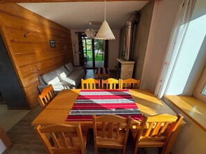 Un comedor con una mesa y sillas de madera, un banco y vistas al exterior a través de un ventanal.