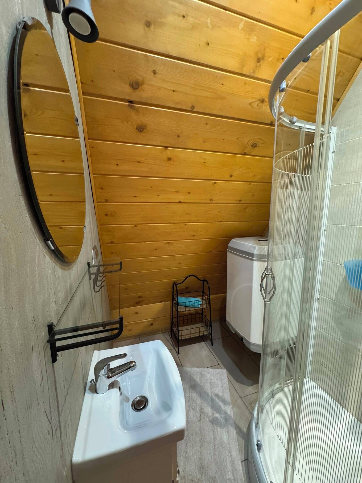 Une petite salle de bain avec un lavabo blanc, un miroir, des toilettes et un espace douche.