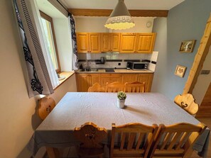 A compact kitchen with wooden cabinets, a dining table with chairs, a hanging pendant light, and a small potted plant. - 2DayStay - ZKP (Zakopane)
