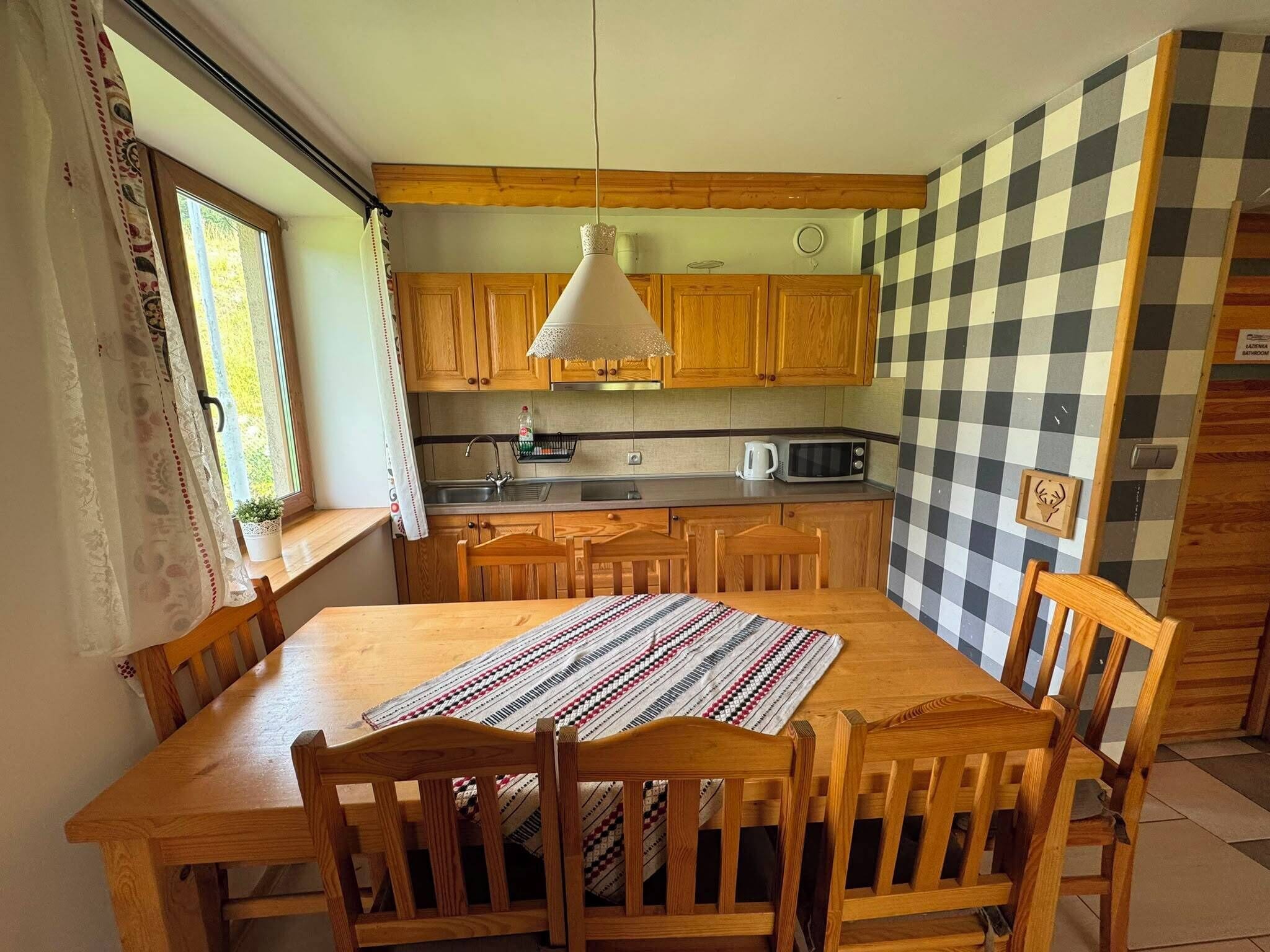 Une cuisine avec des meubles en bois, un four à micro-ondes et un luminaire suspendu.