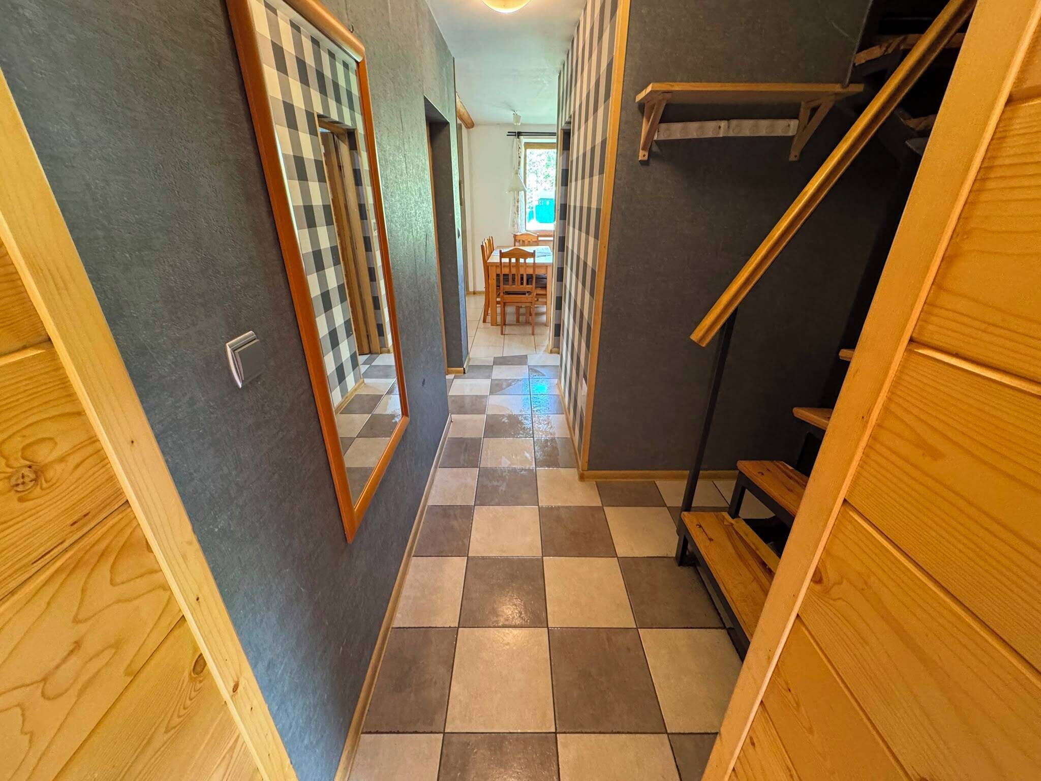 A hallway with checkered flooring, wooden walls, and a staircase.