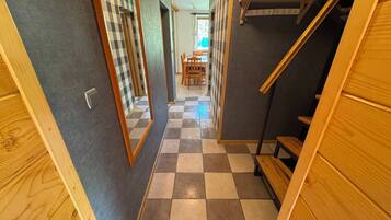 A hallway with checkered flooring, wooden walls, and a staircase.
