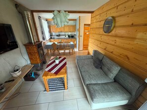 Una sala de estar con un sofá gris, una mesa de centro de madera y un comedor con sillas y mesa de madera.