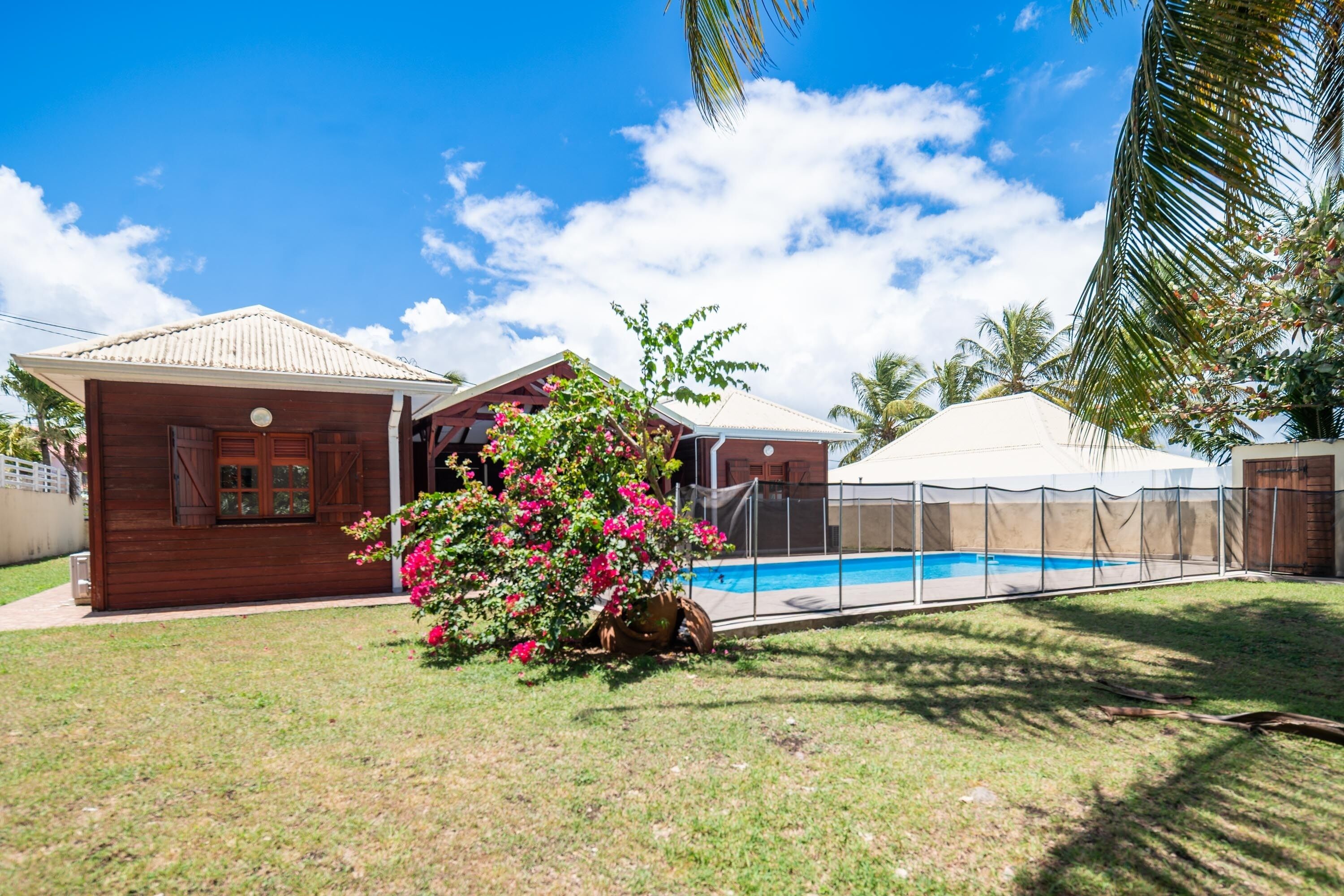 Una propiedad residencial con piscina, casa de madera y zona cubierta.