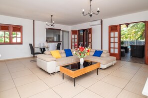 A living room with a sofa set, a coffee table, and a vase of flowers. - L'Echappée Tropicale - Maison avec piscine privée (Le Moule)