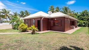 A two-story wooden house with a satellite dish, surrounded by a well-maintained lawn and palm trees. - L'Echappée Tropicale - Maison avec piscine privée (Le Moule)