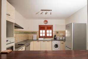 Eine moderne Küche mit Edelstahlkühlschrank, Einbauofen, Waschmaschine und Kaffeemaschine.