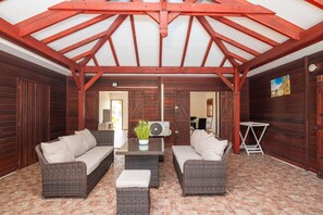 Eine überdachte Terrasse im Freien mit Korbmöbeln und Deckenventilator.