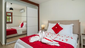 A hotel room with a bed, a bedside table with a lamp, a mirror, and a wardrobe. - L'Echappée Tropicale - Maison avec piscine privée (Le Moule)