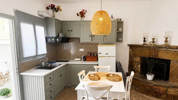 A kitchen with a dining area, a fireplace, and a hanging light fixture. - The Yellow Donkey, Koumeika Traditional Gem Samos (Koumeika)