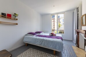 A bedroom with a bed, a window, a shelf with books, and a mirror. - Les Muriers - Maison avec terrasse proche plage (Villerville)