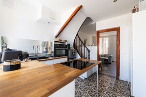 Een moderne keuken met een houten aanrechtblad, roestvrijstalen apparatuur en een zwarte oven.