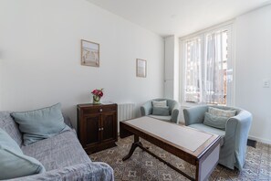 Een woonkamer met een bank, fauteuils, een salontafel en een kast.