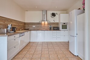 Una cocina moderna con armarios blancos, una campana extractora de acero inoxidable, un microondas y un horno empotrado.