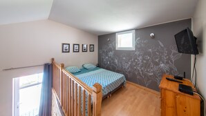 Ein Schlafzimmer mit einem Bett, einem Holztisch, einem Fernseher und einem Fenster.