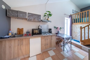 Una cuina compacta amb rentaplats integrat, fogó de gas, cafetera i un petit menjador amb taula i cadires.