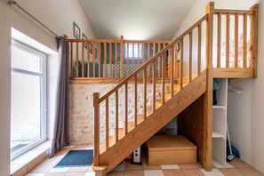 A staircase leading to a loft bedroom with a wooden railing, a window with curtains, and a tiled floor. - Le Gîte Mezzanine - À 30 min du Futuroscope (Chalandray)