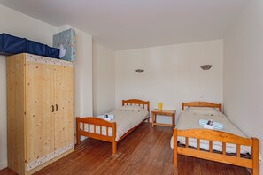 A room with two wooden beds, a wardrobe, and a small table. - Le Clos de Bidache - Jolie maison en pierre pour 5 (Bidache)