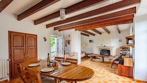 A spacious dining area with a wooden table and chairs, a kitchen with a fireplace, and a view of the outdoors.