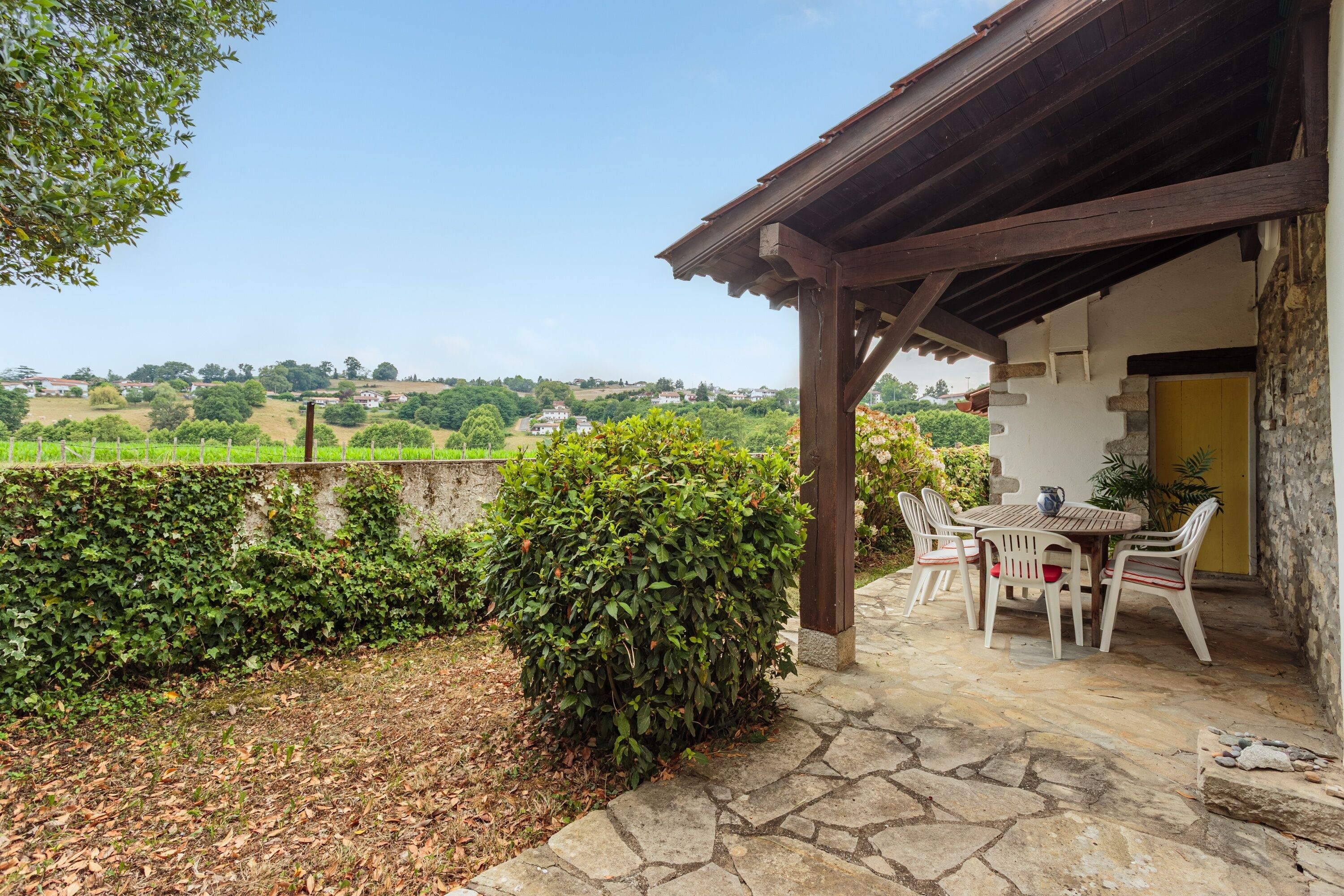 A covered outdoor seating area with stone flooring, a table, and chairs.