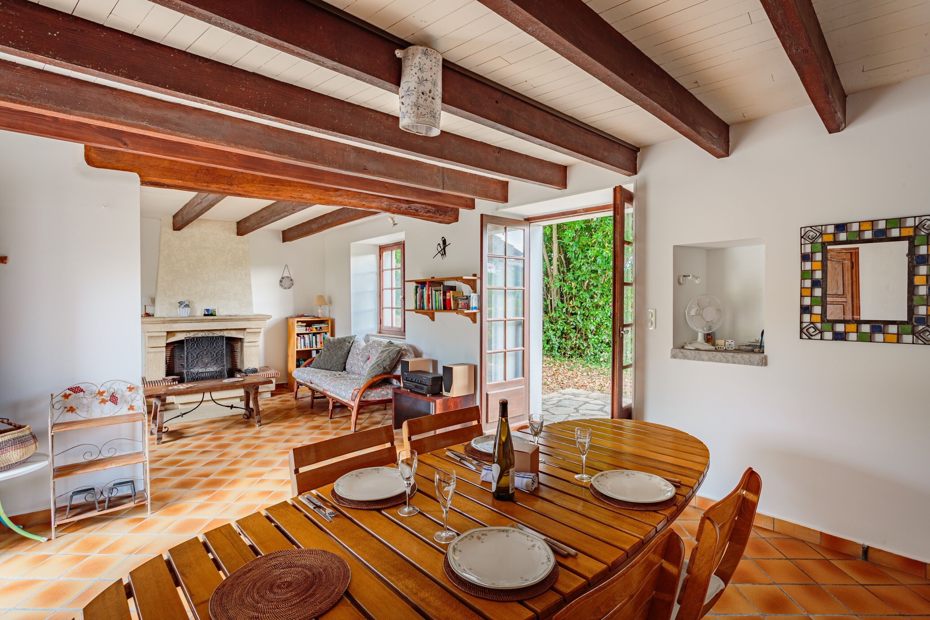 A dining area with a wooden table set for two, a fireplace, and a view of the outdoors.