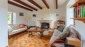 A cozy living room with a fireplace, a sofa, a coffee table, and a bookshelf.