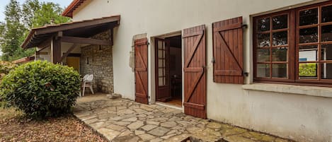 A building with a stone facade, wooden shutters, and a stone-paved entrance.