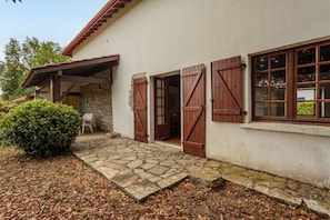 A building with a stone facade, wooden shutters, and a stone-paved entrance. - Le Clos de Bidache - Jolie maison en pierre pour 5 (Bidache)