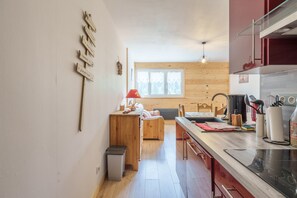 Uma cozinha compacta com armários de madeira, uma área de refeições com um banco e uma janela que oferece luz natural.