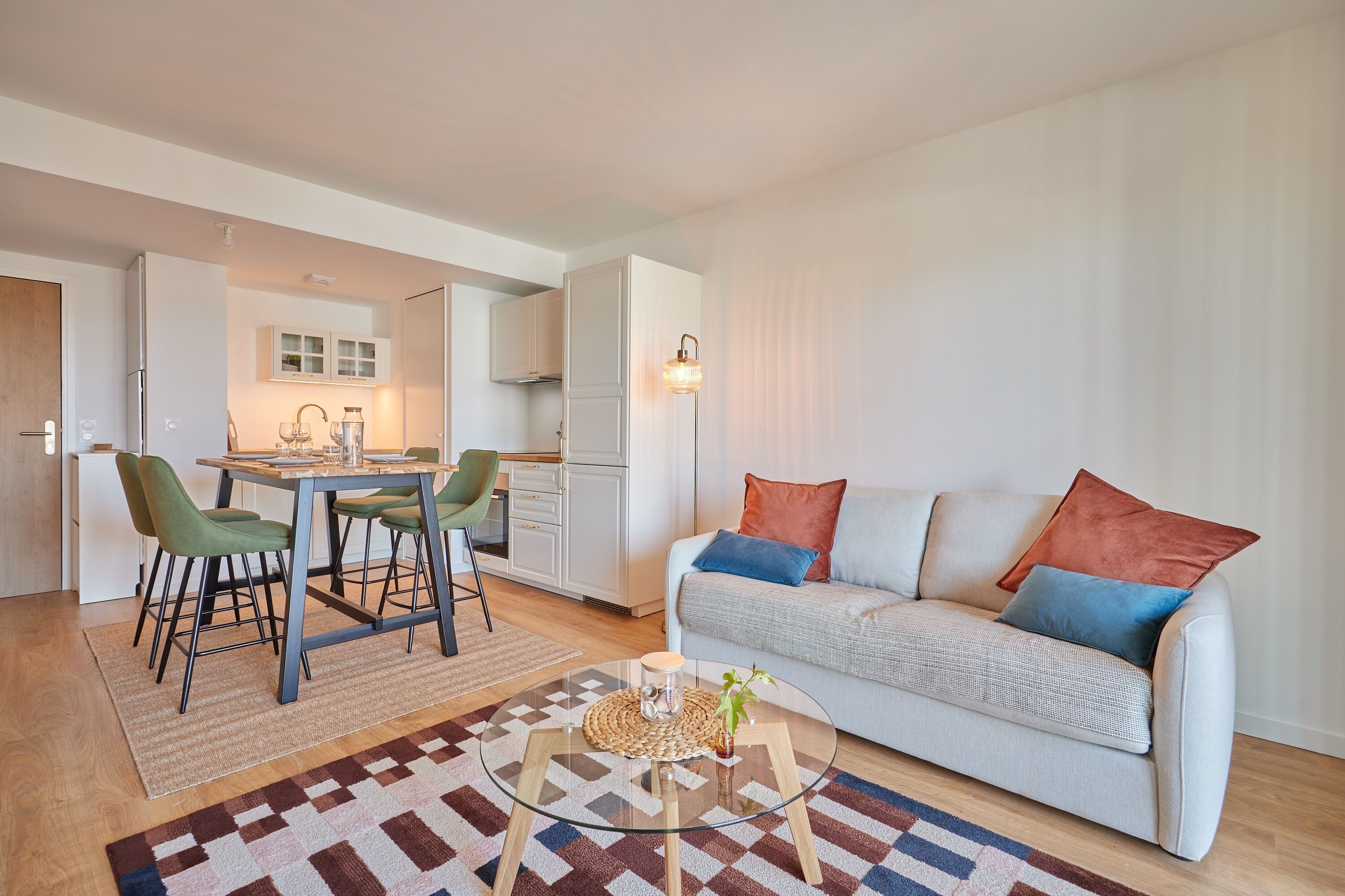 A modern living room with a sofa, a coffee table, and a dining area with chairs and a table.