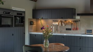 A modern kitchen with grey cabinets, a built-in oven, and a dining area with a round table and chairs.