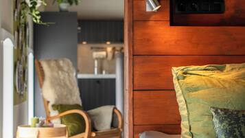 Un dormitorio con cabecera de madera, cama con ropa de cama verde, una silla y un escritorio.