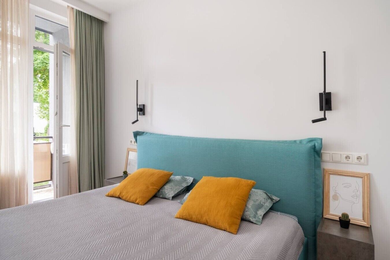 Ein Schlafzimmer mit einem Bett, zwei Kissen, einem Nachttisch, einer Wandlampe und einem Fenster mit Vorhängen.