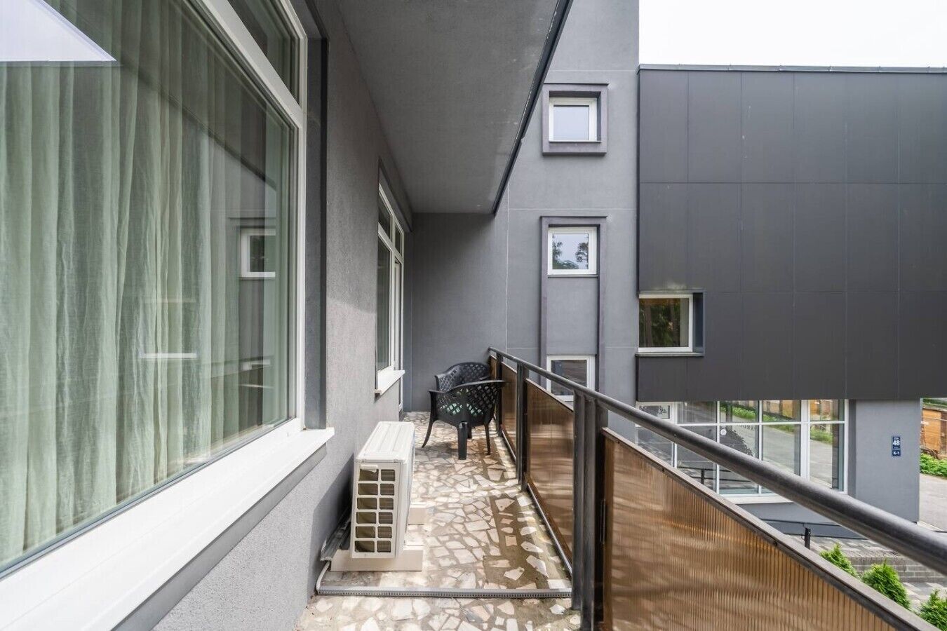 A balcony with a chair, a small table, and a window with curtains.