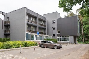 Un bâtiment moderne doté d’un parking, avec une voiture garée devant.