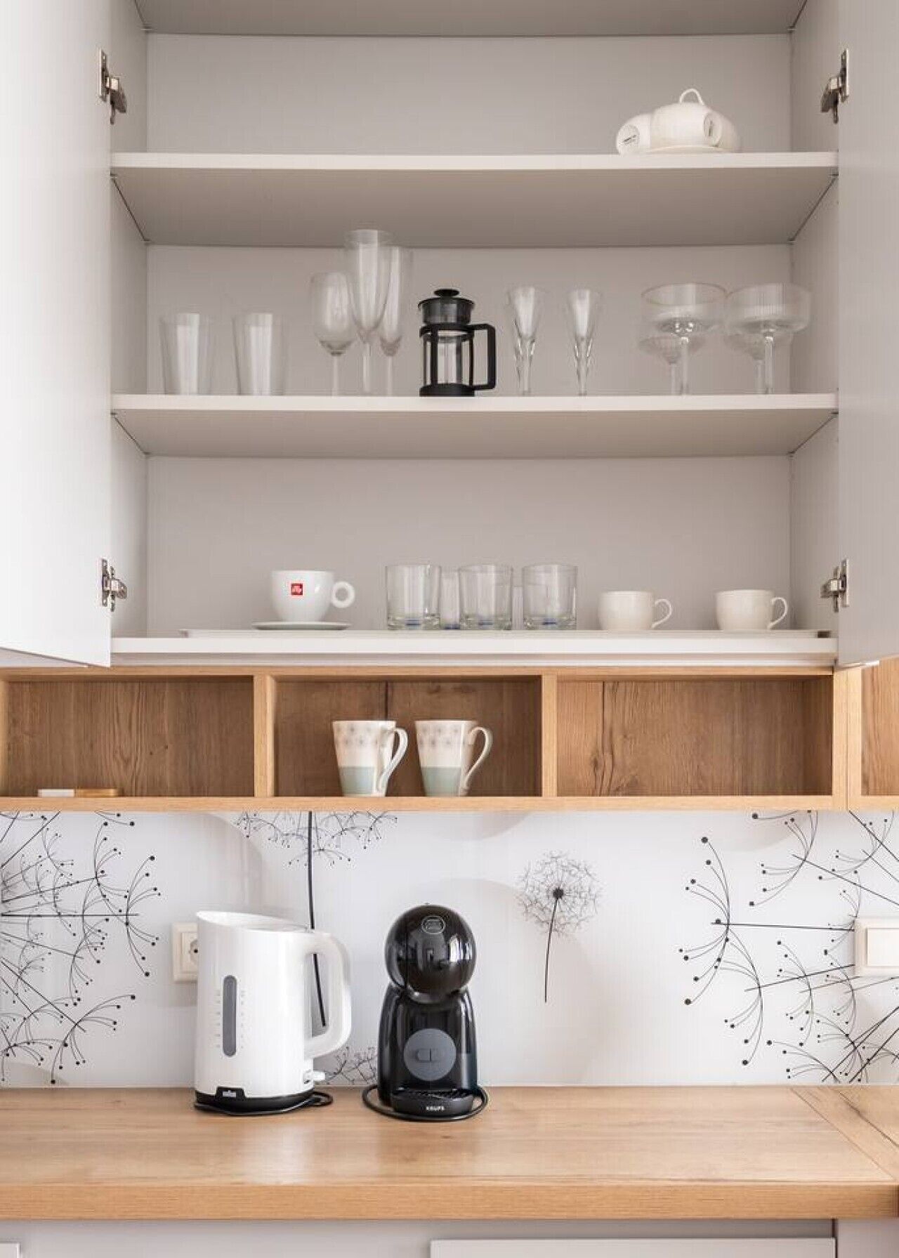 Eine Küche mit weißen Schränken, einer Kaffeemaschine und einem Wasserkocher auf der Arbeitsfläche.